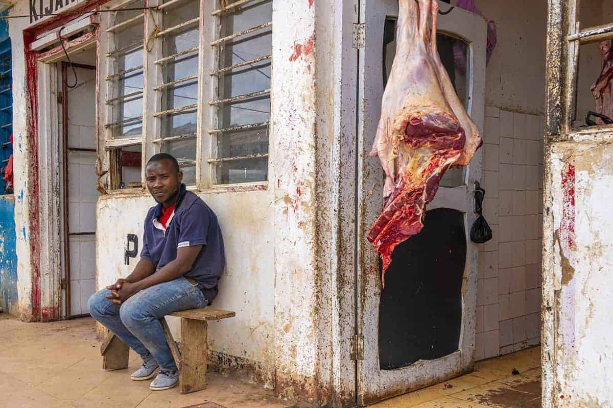 Fotoreis Tanzania - Man zit voor slagerij Fotoreis Tanzania - Man zit voor slagerij