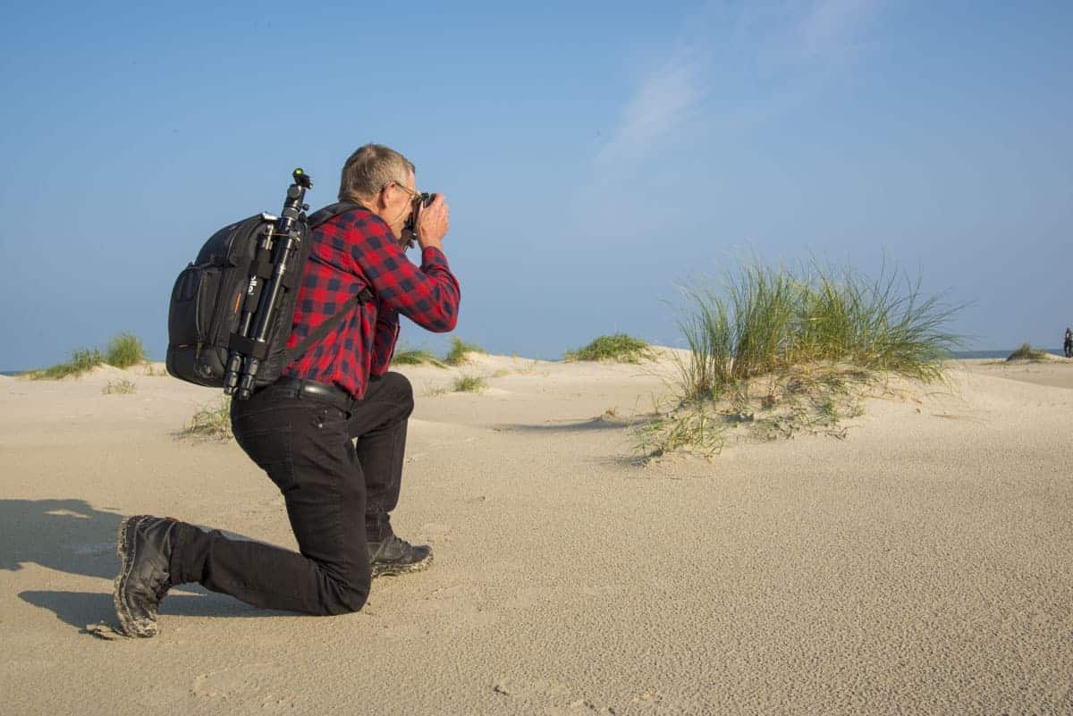 Fotoweekend Ameland - Man fotografeert knielend in het zand Fotoweekend Ameland - Man fotografeert knielend in het zand