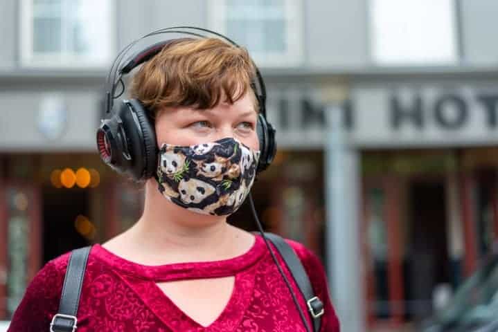 Meisje met mondkap en koptelefoon wacht op de bus - Straatfotografie Groningen